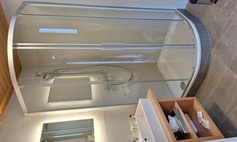 A modern bathroom with a shower cubicle and a sink. The space is bright and friendly designed.