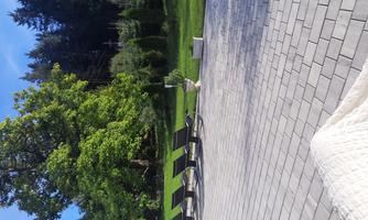 A quiet outdoor area with loungers and a green lawn. In the background, there are trees and a clear blue sky.
