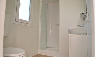 A modern bathroom with a shower, a sink, and a toilet. Bright walls and a window create a friendly atmosphere.
