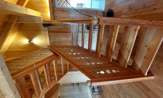 A wooden staircase with round cutouts leads to an open space. The area features warm wood tones and plenty of light.