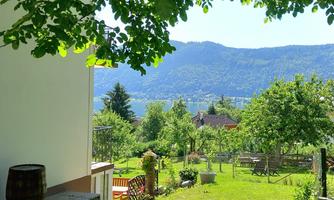 A beautiful garden with green meadows and trees, surrounded by mountains. In the foreground, there is a bench and a barrel.