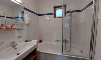 A bright bathroom with a shower and bathtub. It features modern sanitary facilities and practical storage spaces.