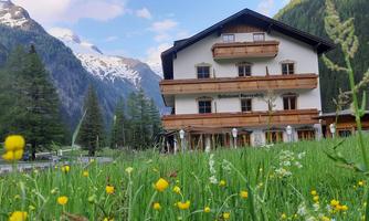 A picturesque hotel in the mountains, surrounded by green meadows and snow-capped peaks. The landscape radiates tranquility and a connection to nature.