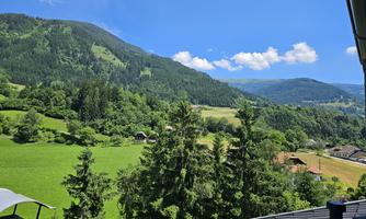 A picturesque landscape with green hills and wooded mountains. The sky is clear and sunny, ideal for a relaxing day in nature.