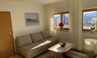 A cozy living room with a sofa and a coffee table. Large windows let in plenty of light and offer a beautiful view.