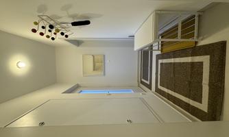 A bright hallway with white walls and a modern table.  
Stylish carpets are laid on the floor, and a colorful hanger is hanging on the wall.