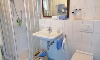 A modern bathroom with a shower, sink, and toilet. Fresh towels and a large mirror are provided.