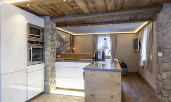 Modern kitchen with white cabinets and a wood and stone accent.  
Bright lighting and an inviting ambiance create a cozy atmosphere.