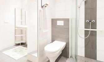 A modern bathroom with a bright tiled floor and a glass shower. The walls are in neutral colors, and there is a towel-friendly area.
