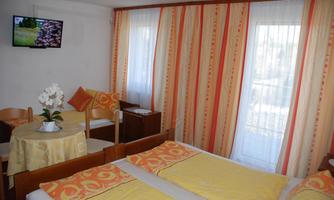 A cozy room with two beds and yellow blankets. There is a table, chairs, and a TV on the wall.