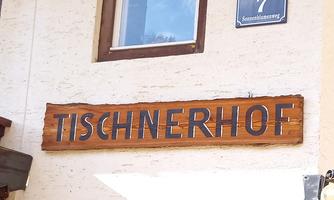 A wooden sign with the inscription "TISCHNERHOF". It is located on a building wall.