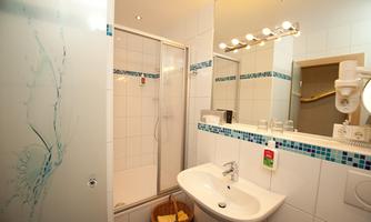 A modern bathroom with a shower and a sink. Bright tiles and attractive lighting create a friendly atmosphere.