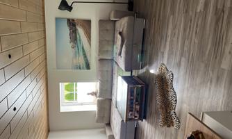 A bright living room with a comfortable gray sofa and a colorful table. A large picture of a beach hangs on the wall.