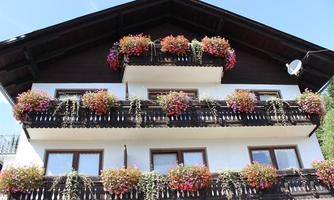 A beautiful house with several balconies decorated with colorful flowers. The sky is clear and it looks like a sunny day.