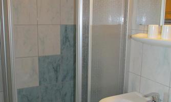 A bathroom with a shower and a sink. The walls are tiled in light colors.