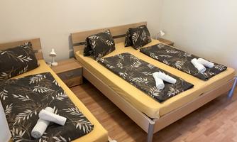 A simple bedroom with three beds and modern bedding. Towels are neatly placed on the beds.