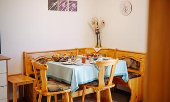 An inviting dining area with wooden furniture and light blue tablecloths. Various dishes and drinks are arranged on the table.