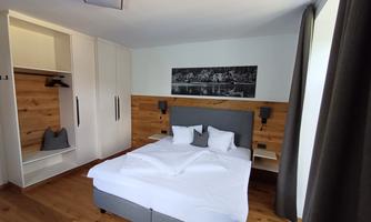 A modern bedroom with a large bed and wood paneling. The furnishings are bright and functional, ideal for a comfortable stay.