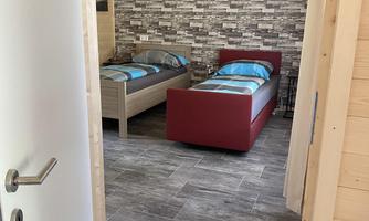 A cozy bedroom with two beds and modern design. The walls are decorated with a decorative stone pattern.