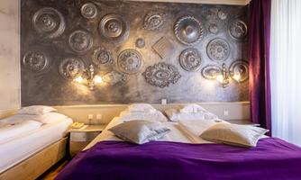 A modern bedroom with a large bed, surrounded by decorative wall panels. The room design is elegant with purple accents and soft lighting.