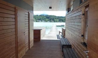 A beautiful wooden walkway leads to a tranquil body of water. The walls are made of wood and allow plenty of natural light to enter.