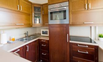 A modern kitchen with wooden cabinets and a stainless steel kitchen line. The equipment includes an oven, a sink, and a microwave.
