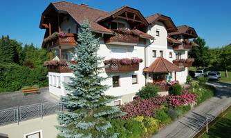 A beautiful multi-story residential building with balconies and blooming plants. Surrounded by green nature and well-kept gardens.