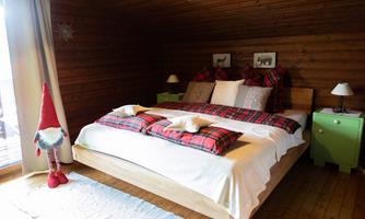 A cozy bedroom with a large bed and colorful cushions. In the room, there is a green nightstand and a Christmas figurine.