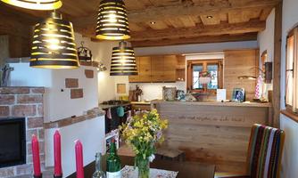 A cozy room with a wooden beam ceiling and modern lamps. The table is lovingly set and decorated with fresh flowers.