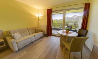 A cozy living room with a sofa, a table, and chairs.  
Through the windows, you can see the mountains and the beautiful landscape outside.