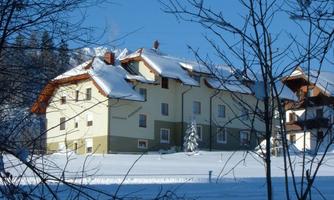 A cozy building in the snow, surrounded by a wintry landscape. The clear blue sky complements the serene scene.
