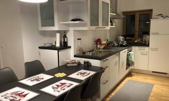 A modern kitchen with a dining table and chairs. The room has bright walls and a cozy atmosphere.