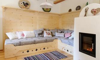A cozy living space with wooden walls and a seating area. A modern fireplace provides a warm atmosphere.