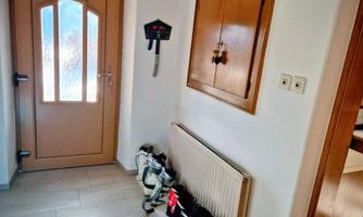 An entrance area with a wooden door and a radiator. Next to the door are several pairs of shoes.