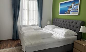 An inviting bedroom with a modern bed and cozy furnishings. The colored wall and the picture give the room a fresh atmosphere.