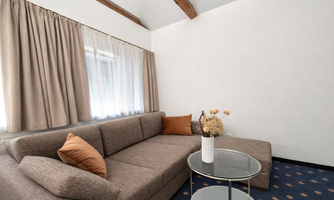 A cozy living area with a gray sofa and decorative cushions. A round table with a vase stands in the center of the room.