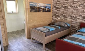 A cozy room with two single beds and modern decorations. The walls are adorned with wooden panels and a decorative stone pattern.