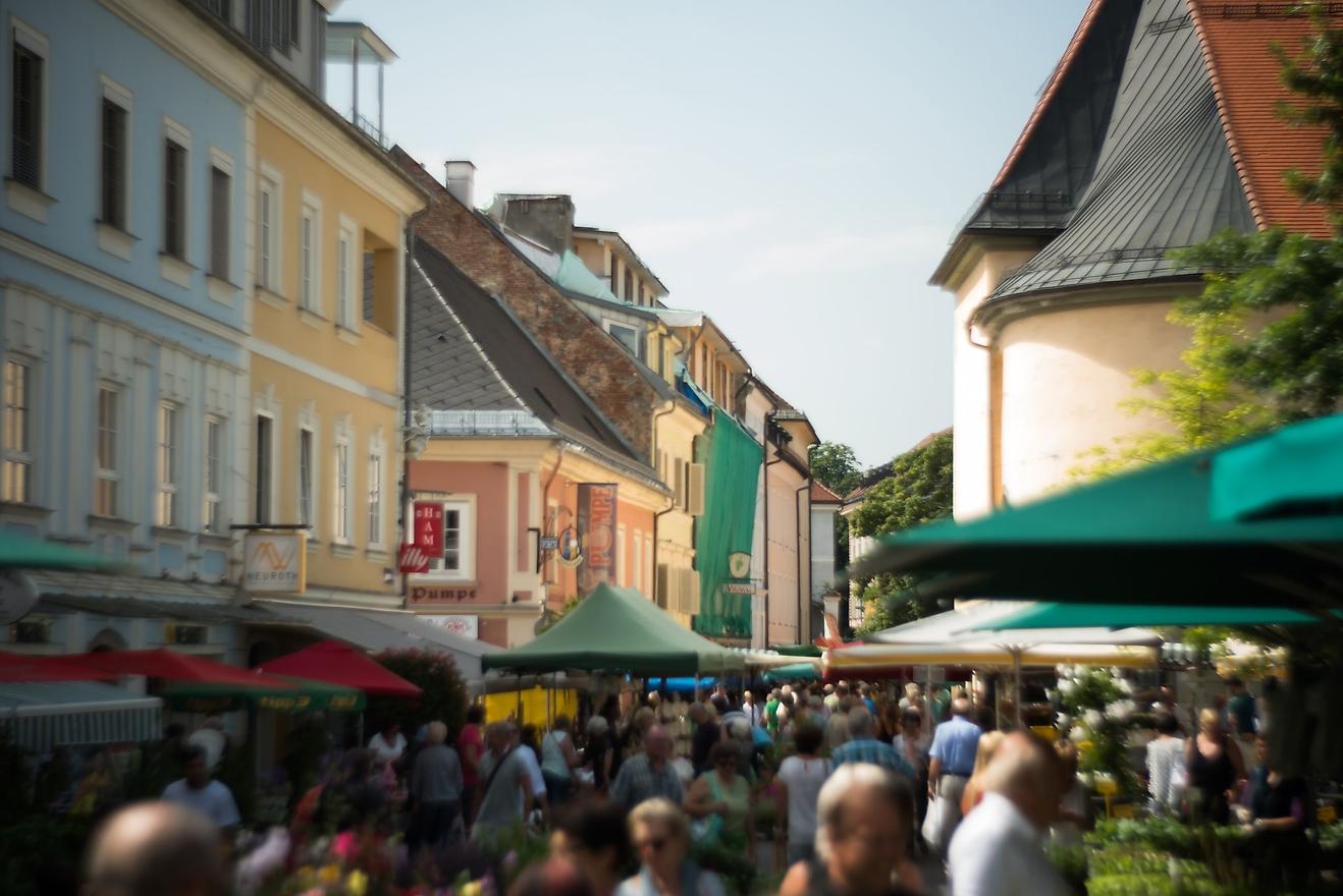 Markttreiben in der Fußgängerzone von Wels mit vielen Menschen und bunten Häusern.