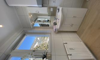 A modern bathroom with a sink and a large mirror. Large windows offer a view of the mountains and let in plenty of light.
