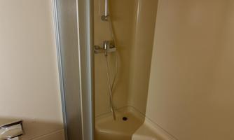 A simple shower in a bathroom. The walls are beige and the shower enclosure consists of glass sliding doors.