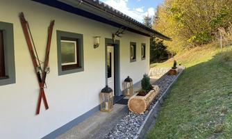 A house with a modern design, decorated with old skis on the wall. The garden is designed with gravel and plants, providing an inviting atmosphere.