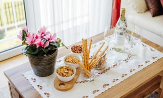 A stylish table with snacks, a bottle of wine, and glasses. A blooming plant adds to the cozy atmosphere.