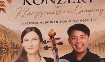 Ein Konzertplakat mit zwei Musikern, die in entspannter Atmosphäre klassische Musik spielen. Im Hintergrund sind eine malerische Landschaft und der Text "Konzert Klanggenuss am Camping" zu sehen.