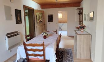 An inviting dining area with a wooden table and chairs. The room is bright and friendly, with pictures on the walls and decorative elements.