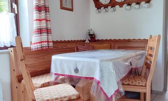 A cozy dining table with chairs in a bright, cheerful kitchen. The walls are made of wood and adorned with decorations.
