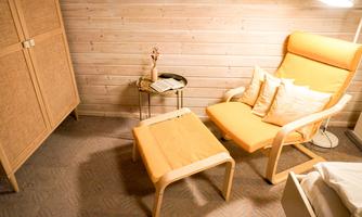 A modern room with a comfortable orange armchair and matching pillows. Next to the armchair is a small table and a decorative wooden cabinet.