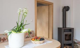 A cozy dining area with a table on which a bowl of fresh fruit sits. In the background, there is an oven and a door leading to the next room.