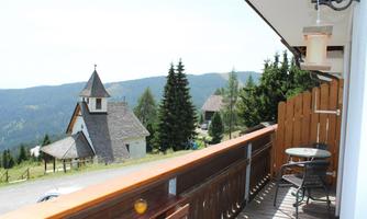 A beautiful view from a balcony of a picturesque landscape. In the background, a small church and wooded hills can be seen.