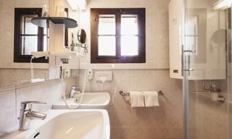 A modern bathroom with two sinks and a shower. Bright tiles and natural light sources create a friendly atmosphere.