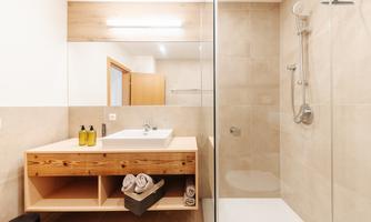 A modern bathroom with a glass shower cabin and a stylish wooden vanity. The neutral tones and clean lines create a relaxing atmosphere.
